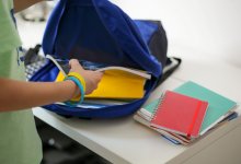 Student putting notebooks in backpack