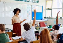 A photo of a few students raising their hands to answer a teacher's question.