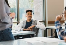 A photo of two high schoolers having a discussion during class.