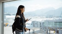 A photo of a high school student waiting for her flight at an airport gate.