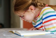 A photo of an elementary student reading a book in her home. empowering elementary readers