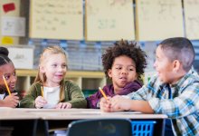 A photo of a small group of elementary students having a discussion about a math problem.