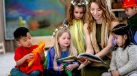 A photo of elementary students in costume and listening to their teacher during an immersive read-aloud.
