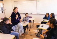 Middle school teacher talking to a group of students in class