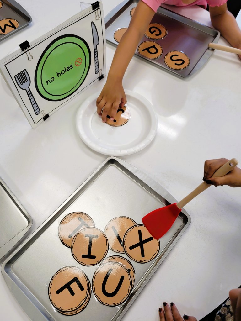 A photo of students playing with alphabet cards shaped like cookies.