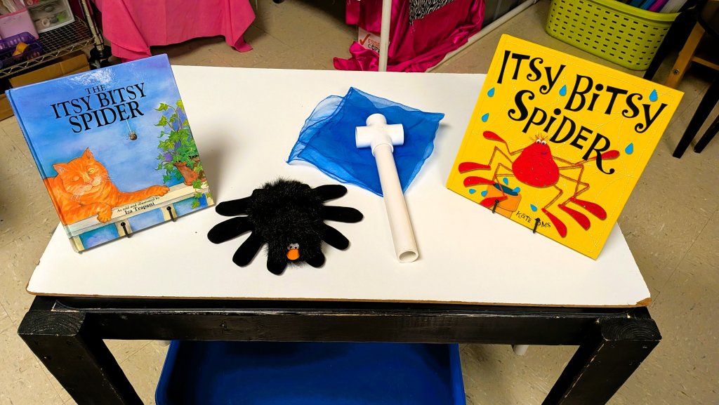 A photo of two "Itsy Bitsy Spider" books with toys relating to the story.