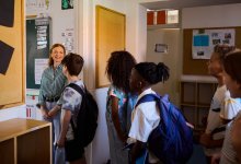 Teacher greeting students as they enter classroom door