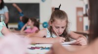 Elementary student writing at her desk