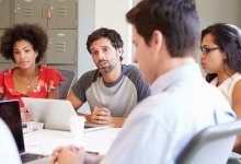 A photo of administrators and teachers referring to their laptops during a meeting.