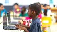 A photo of an elementary student watching a video on a laptop during a blended learning writing workshop.