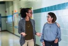 A photo of two teachers having an important discussion in a school hallway.