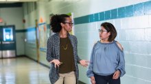 A photo of two teachers having an important discussion in a school hallway.