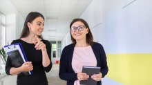 Two women walking together down a school hallway