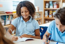 A photo of elementary students engaged and reflective while writing.