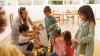 A photo of preschool students cleaning up a classroom