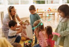 A photo of preschool students cleaning up a classroom