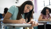 High school student writing at her desk