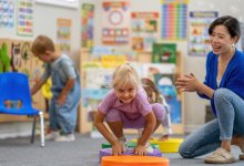 Preschool teacher cheering on student as she jumps across pads