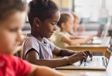 A photo of elementary students working on their laptops during class