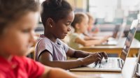 A photo of elementary students working on their laptops during class