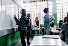 Middle school students engaged in a socratic seminar as one student takes notes on a whiteboard