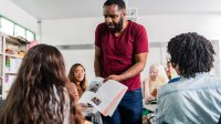 A photo of a teacher prompting his students to further analyze a textbook.