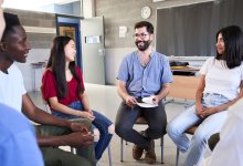 A photo high school students and their teacher sitting in a circle and talking