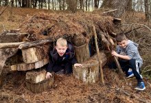 Two children play in an outdoor fort that they built