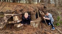 Two children play in an outdoor fort that they built