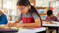 Elementary student writing at her desk