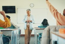 Teacher talking to class with raised hands