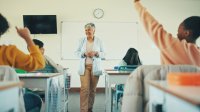 Teacher talking to class with raised hands