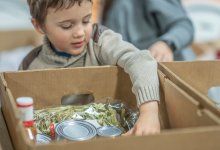 A photo of a young student packing boxes with items to donate