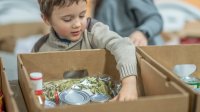 A photo of a young student packing boxes with items to donate
