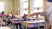 A photo of elementary students attentively listening to their teacher