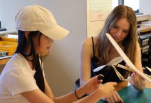 Two high school students working on a model airplane