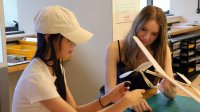 Two high school students working on a model airplane