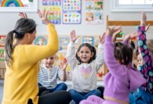 Preschool teacher leading students in a game while sitting on the floor