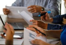 A meeting between school leaders and teachers using printed sheets and laptops