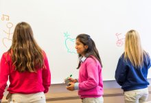A photo of students standing at the board and drawing for a pictionary game