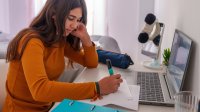 A photo of a high school student highlighting at her desk at home