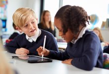 A photo of an elementary student using a tablet to explain a math problem to another student
