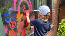 Elementary student finger painting on a window