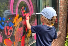 Elementary student finger painting on a window