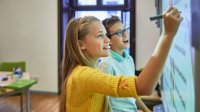 A photo of two elementary students solving a problem together on the board