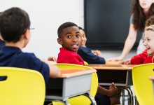 A photo of elementary students turning around to hear a fellow student's comment