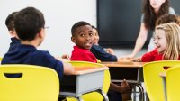 A photo of elementary students turning around to hear a fellow student's comment