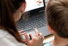 A photo of a teacher guiding an elementary student in a laptop program