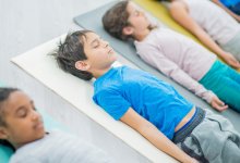 Elementary students lying down on yoga mats