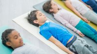 Elementary students lying down on yoga mats